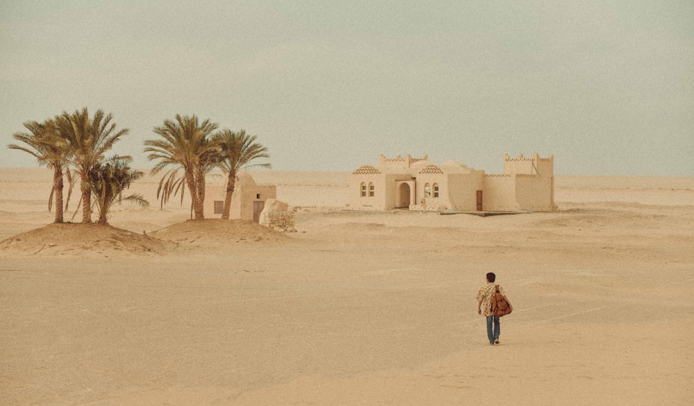 donna in giacca rossa che cammina sulla sabbia durante il giorno