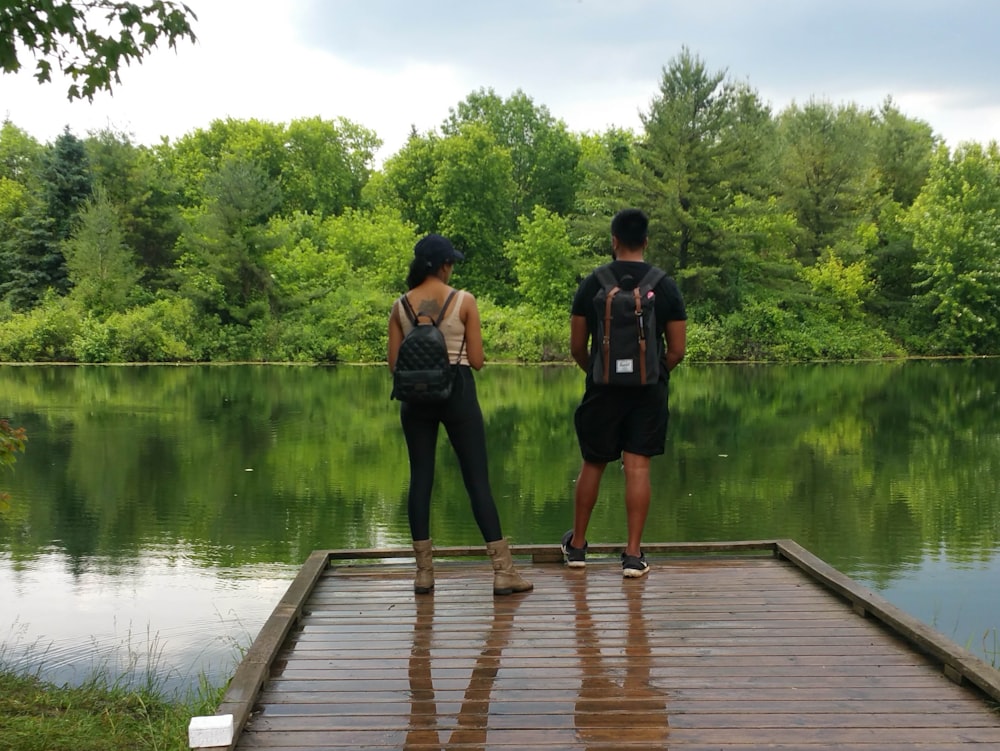 man and woman standing on wooden dock during daytime