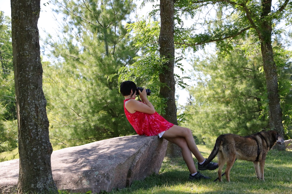 woman in red dress sitting on brown rock during daytime