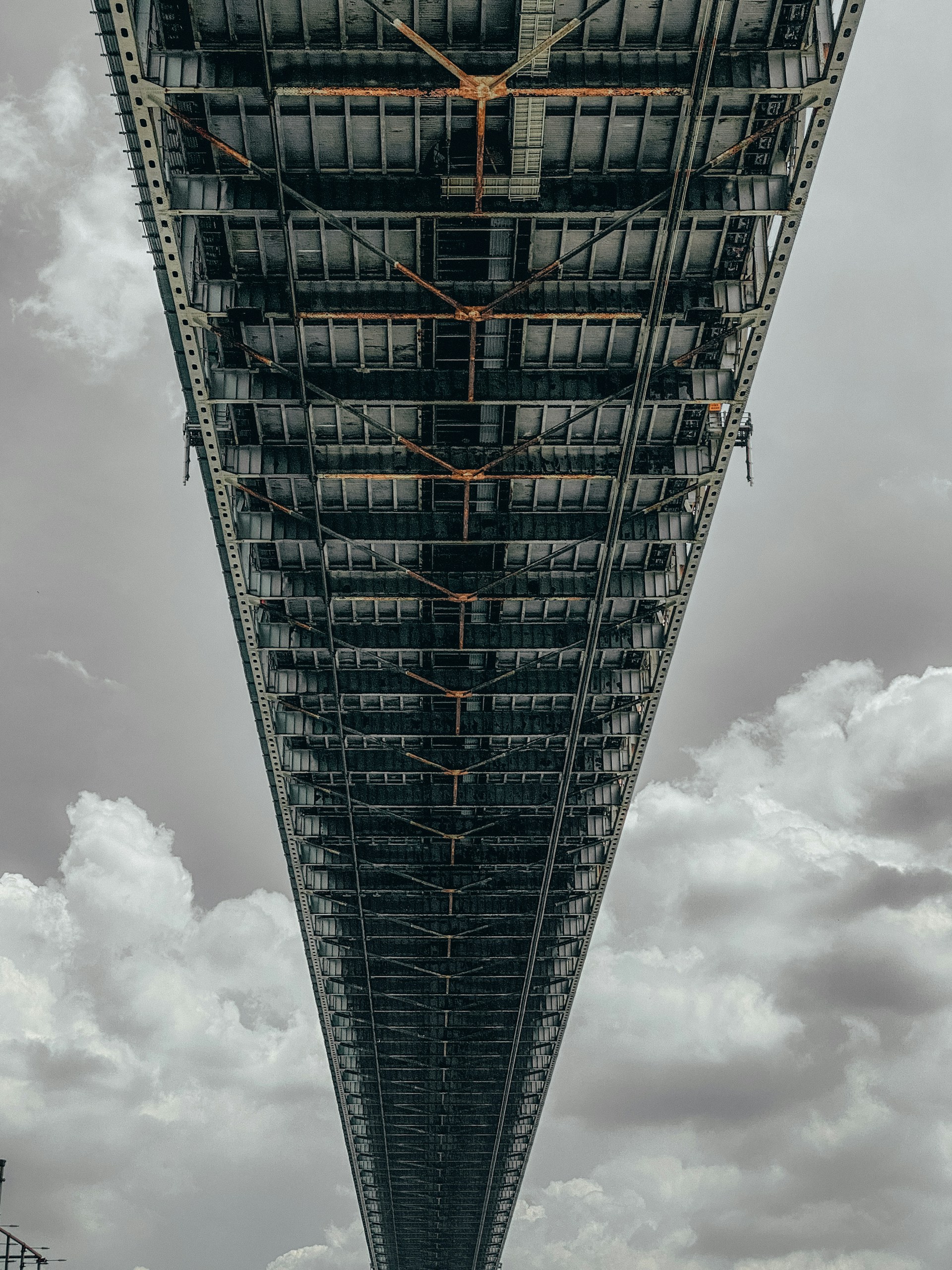 the underside of a large bridge with a sky background