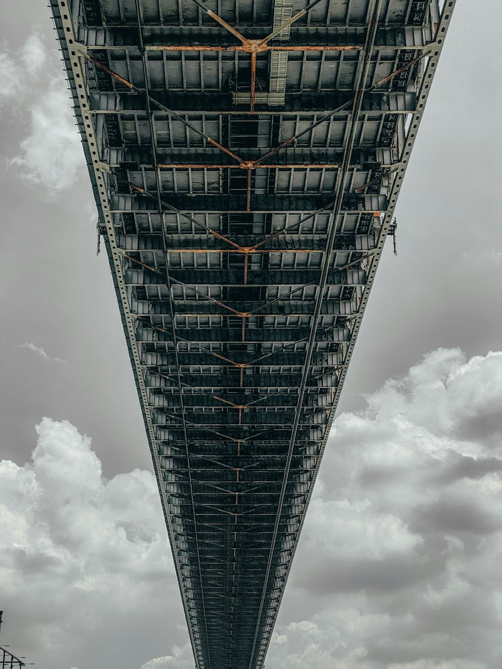 the underside of a large bridge with a sky background