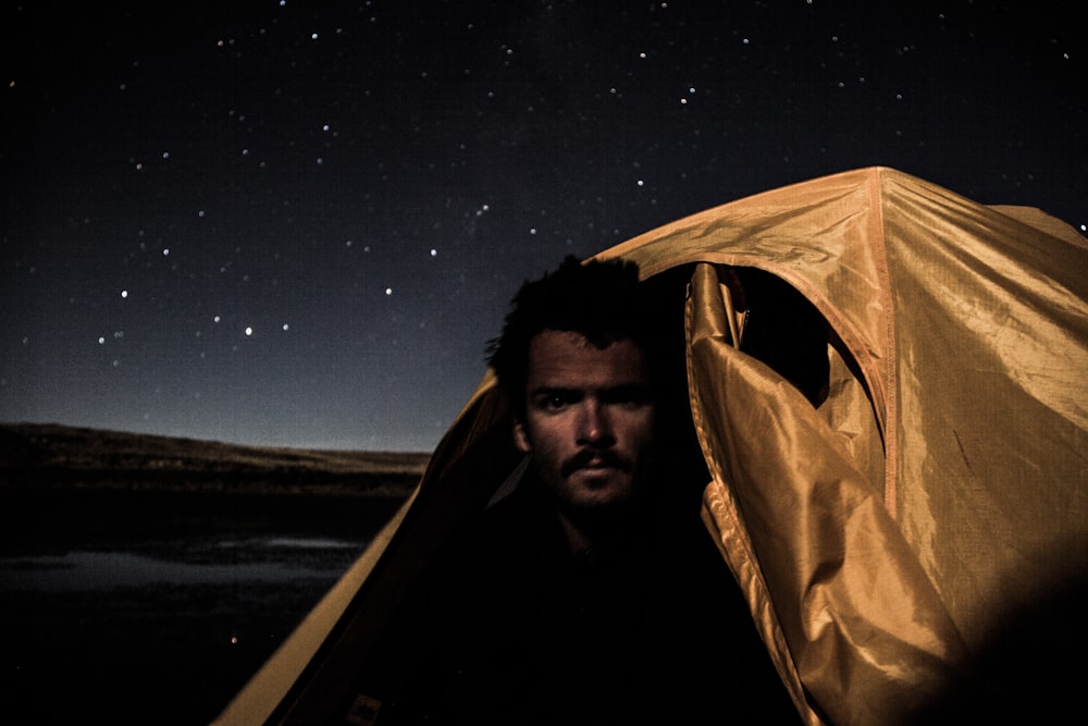 man in brown hoodie inside tent during night time