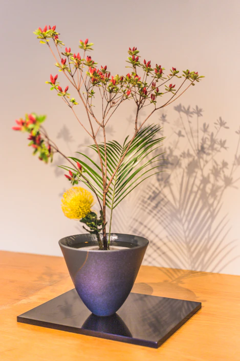 Minimalist floral arrangement with wildflowers and gold-accented vase on a cream surface