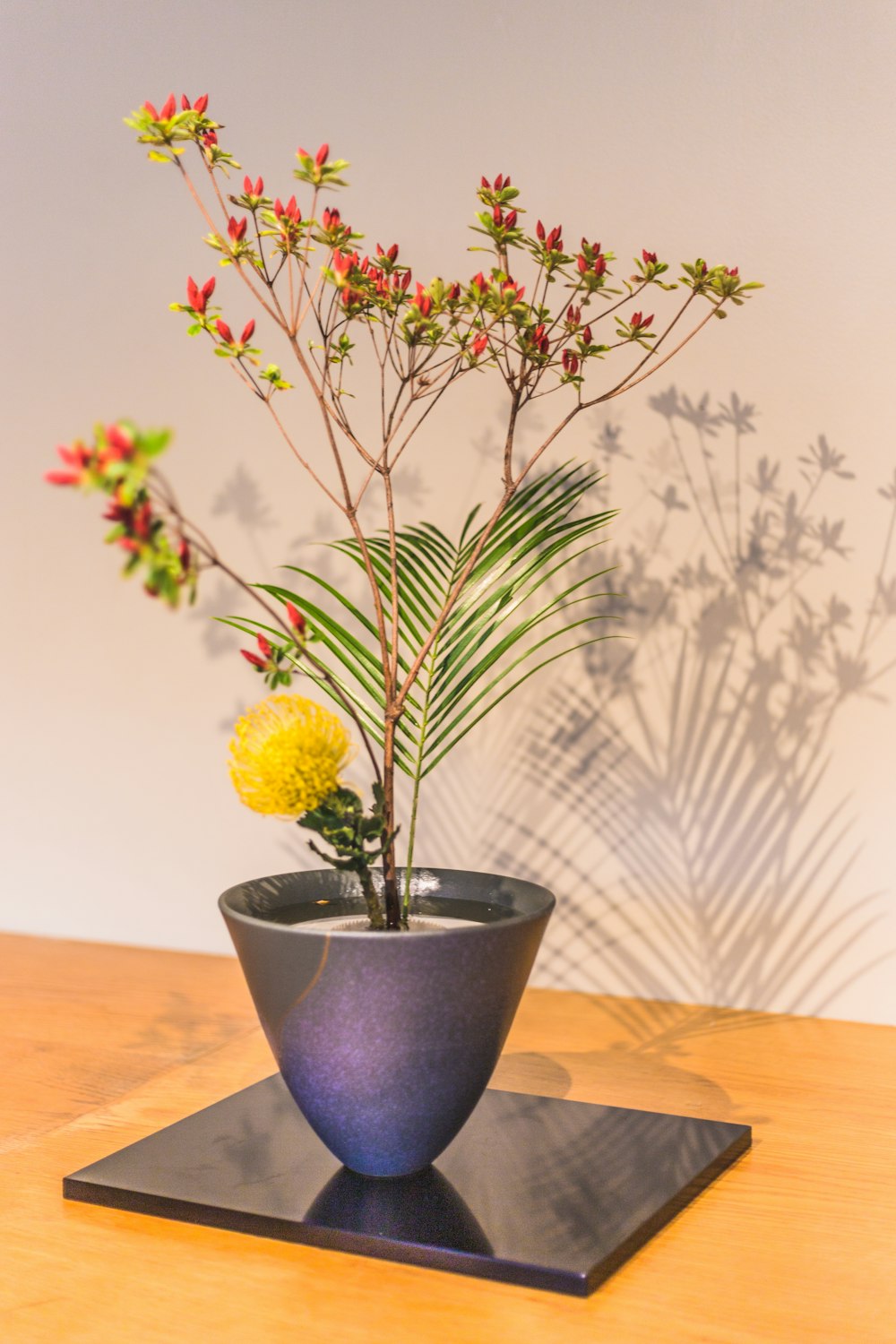 fleurs jaunes dans un vase en céramique bleu sur une table en bois marron