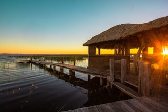 A cozy lodge by the Amazon river at sunset with fishing boats docked nearby.