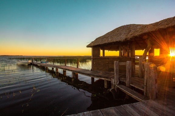 A cozy lodge by the Amazon river at sunset with fishing boats docked nearby.