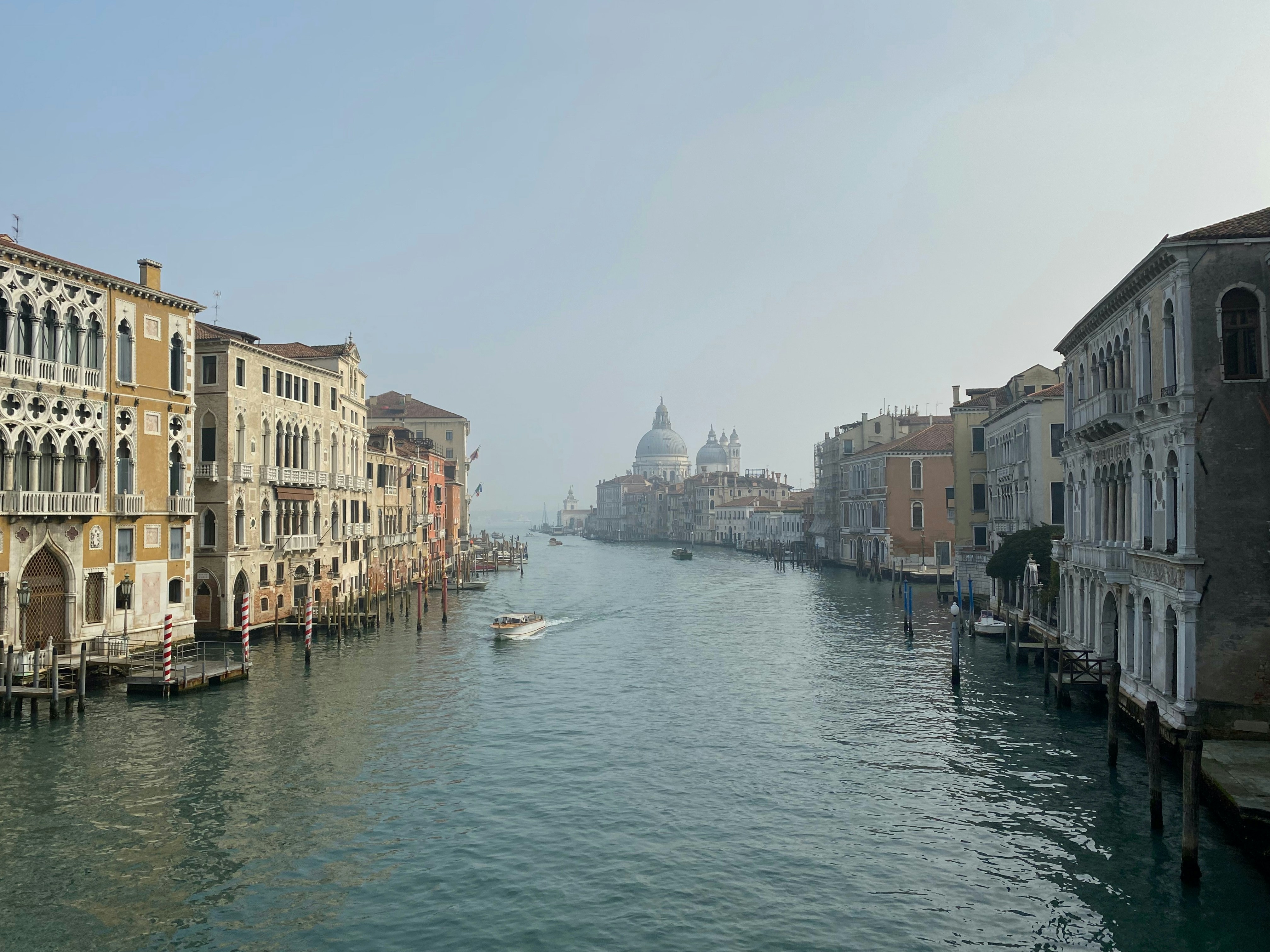 white boat on river between buildings during daytime, Photo taken on a hazy February morning in Venice