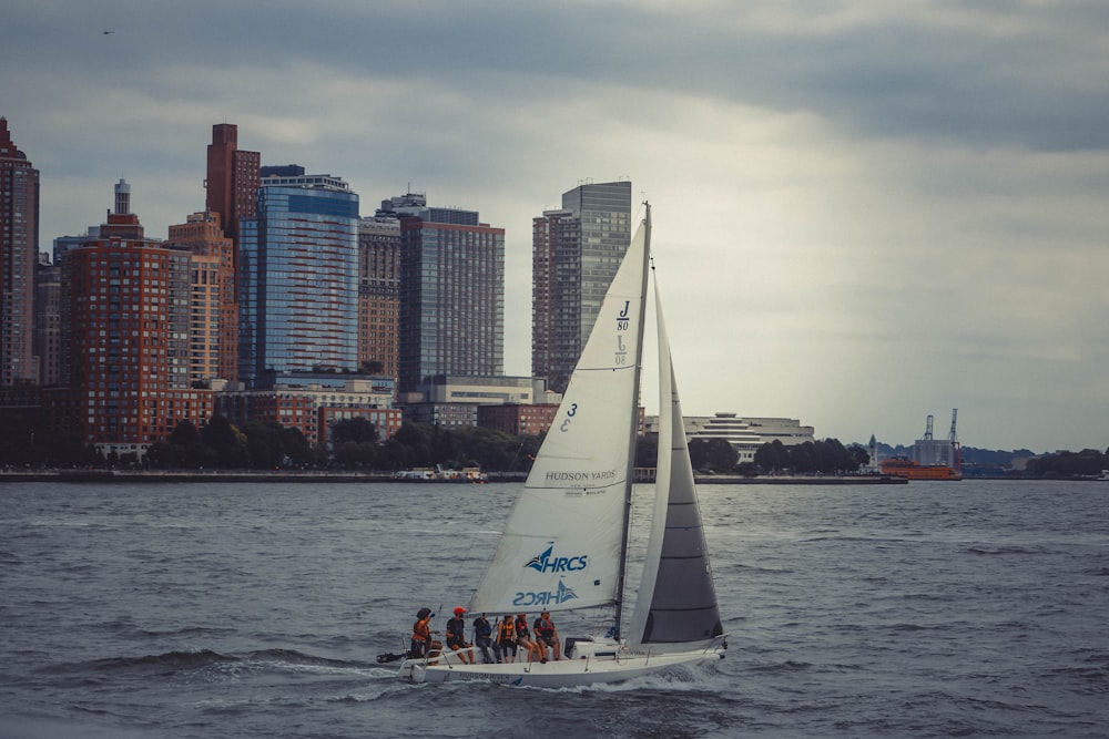 white sail boat on sea near city buildings during daytime