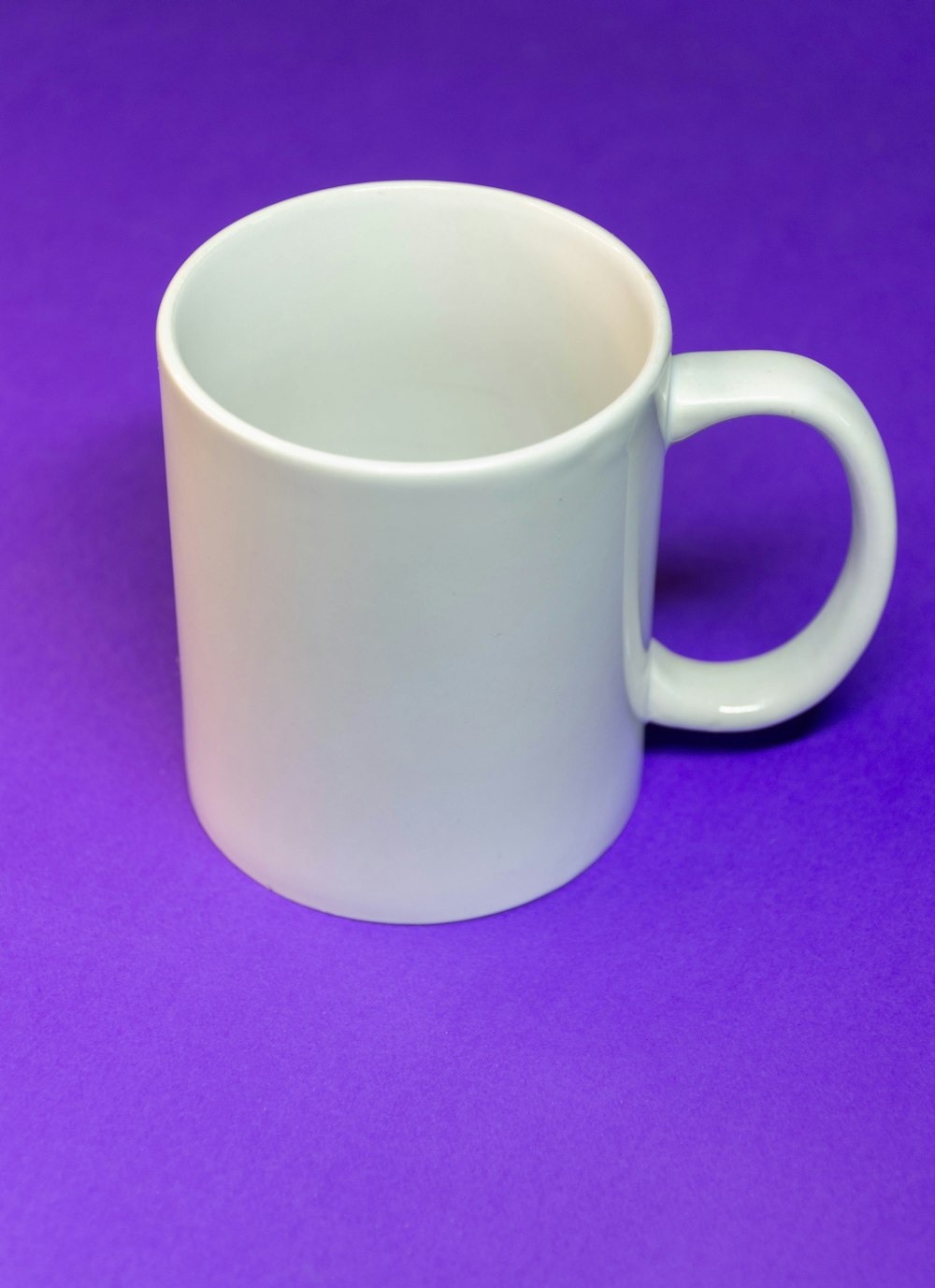 white ceramic mug on purple textile