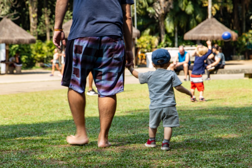 man in gray crew neck t-shirt and red and black plaid shorts standing on green