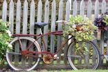 Close-up of a vintage bicycle leaning against a rustic wooden fence surrounded by wildflowers.