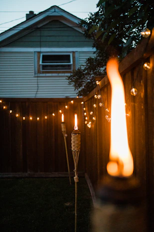 A cheerful backyard scene with friends enjoying a barbecue feast under string lights at dusk.