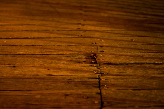 A wooden surface features long, horizontal planks with visible grains and knots. The boards are secured with evenly spaced metal nails, creating a rustic and warm appearance.