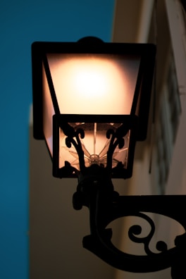 Close-up of a vintage lamplight glowing softly against a twilight sky.