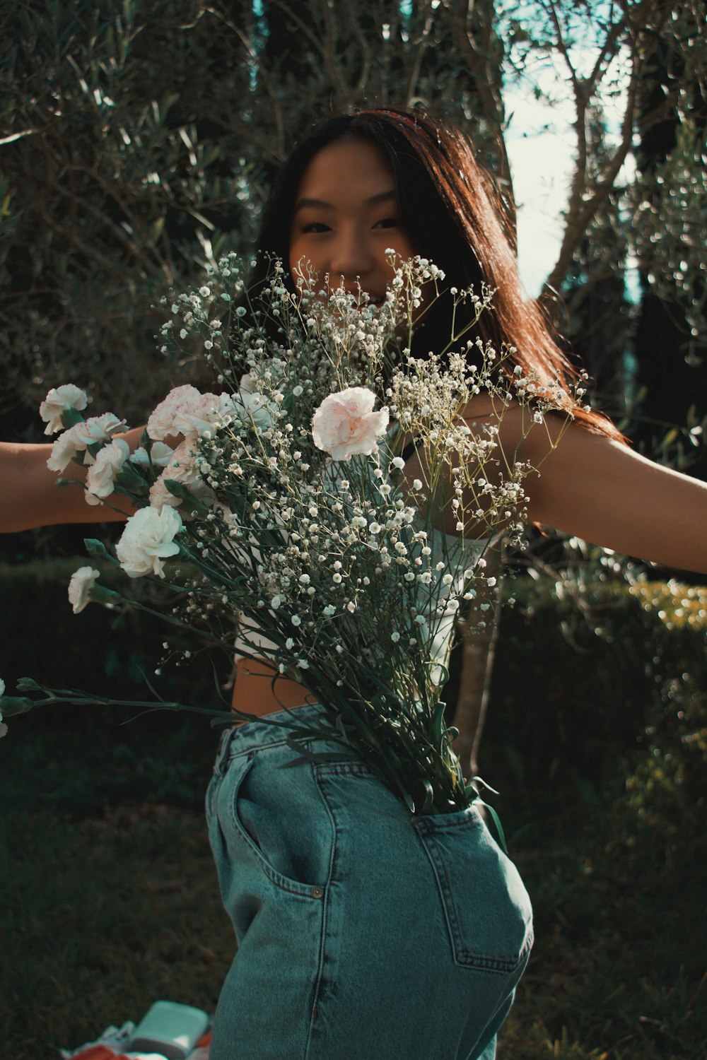 woman in blue denim jacket holding white flowers