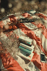 A colorful collection of portable speakers arranged on a picnic blanket in the sun.