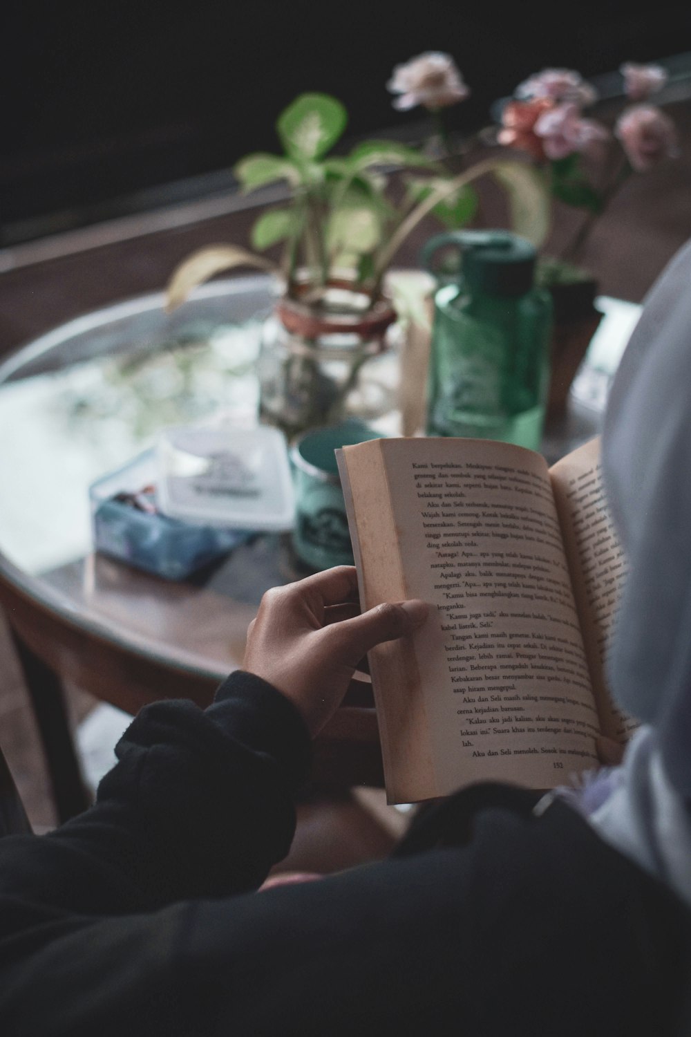 person holding book near brown wooden table