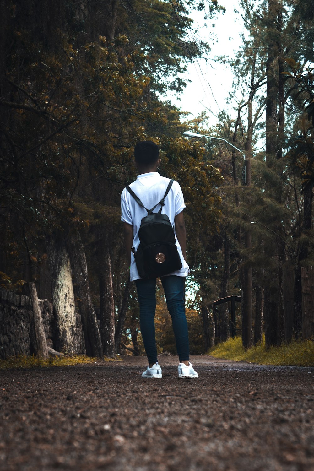 uomo in camicia bianca e pantaloni neri in piedi sul sentiero di cemento grigio