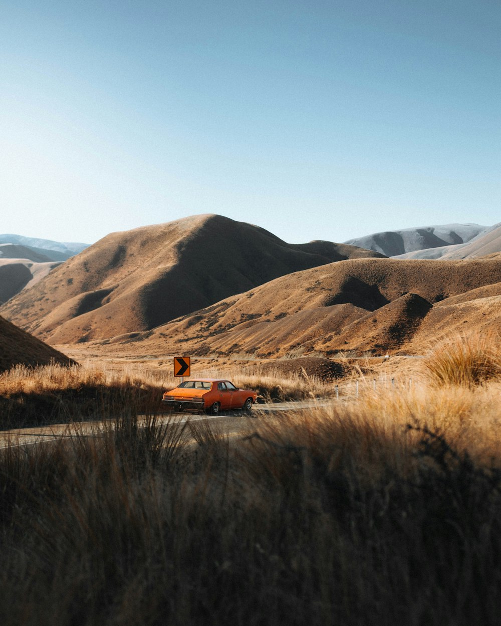 brown car on brown grass field near brown mountain during daytime