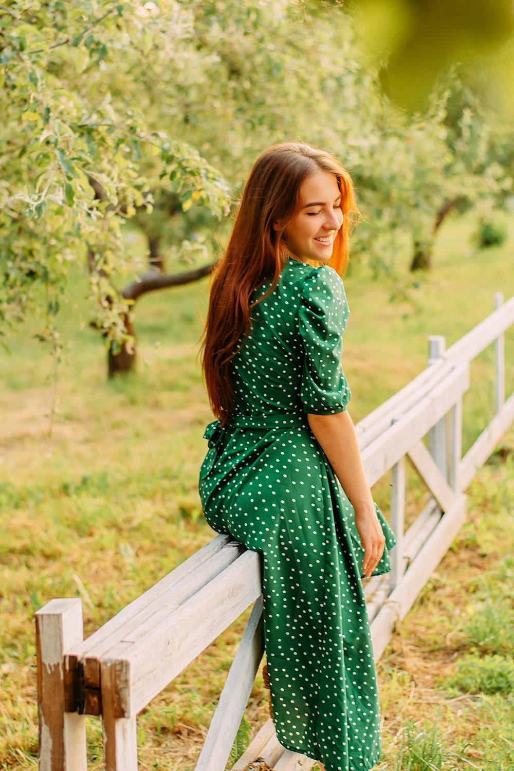 woman in green dress standing on wooden bridge