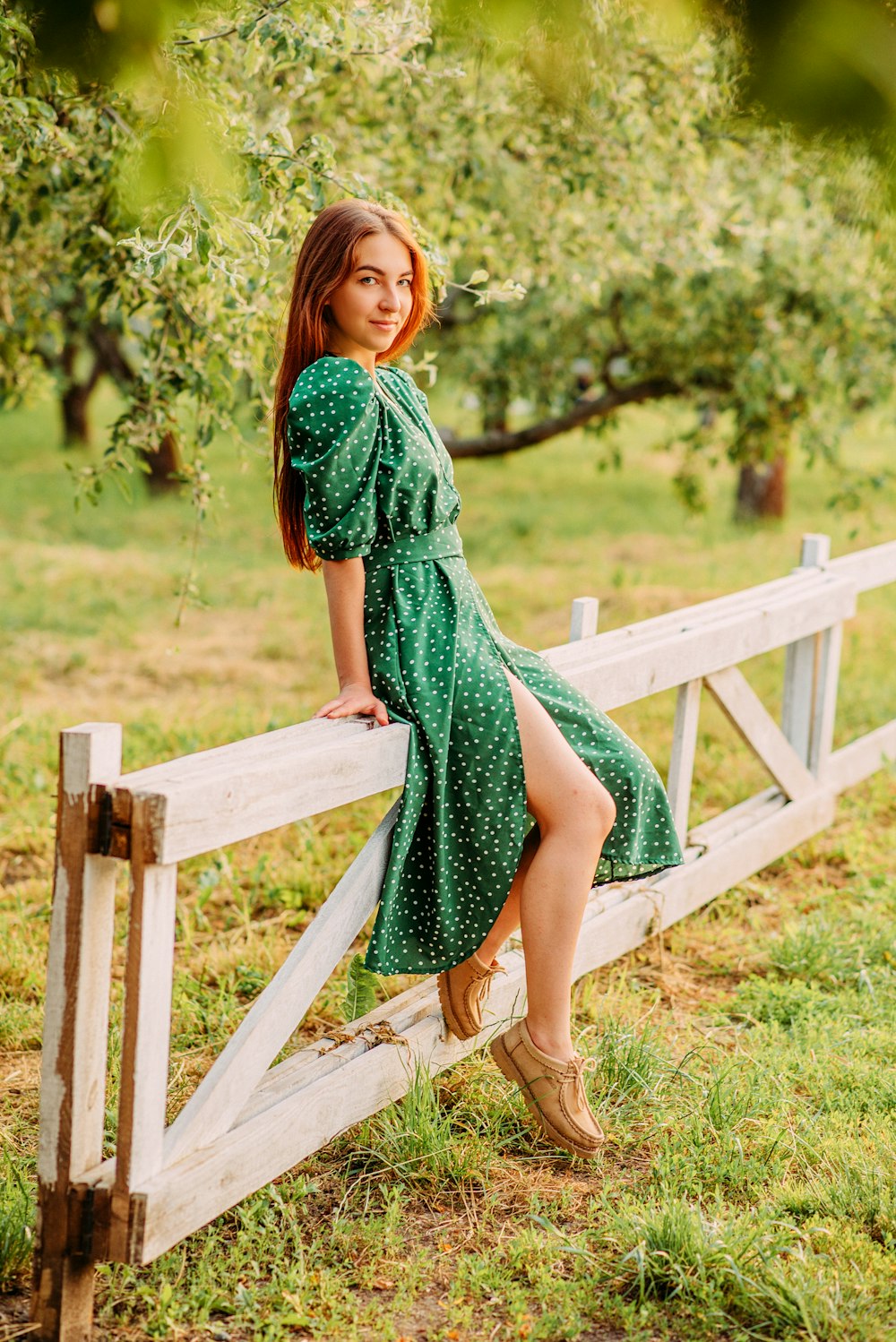 woman in green dress standing on brown wooden bridge during daytime