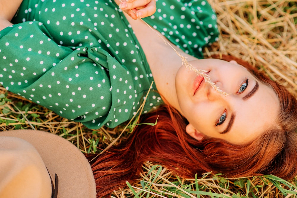 woman in green and white polka dot dress lying on brown grass