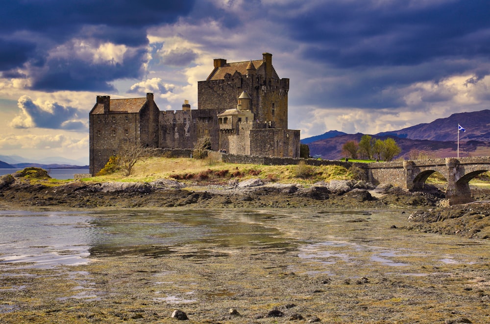 gray concrete castle on body of water under cloudy sky during daytime