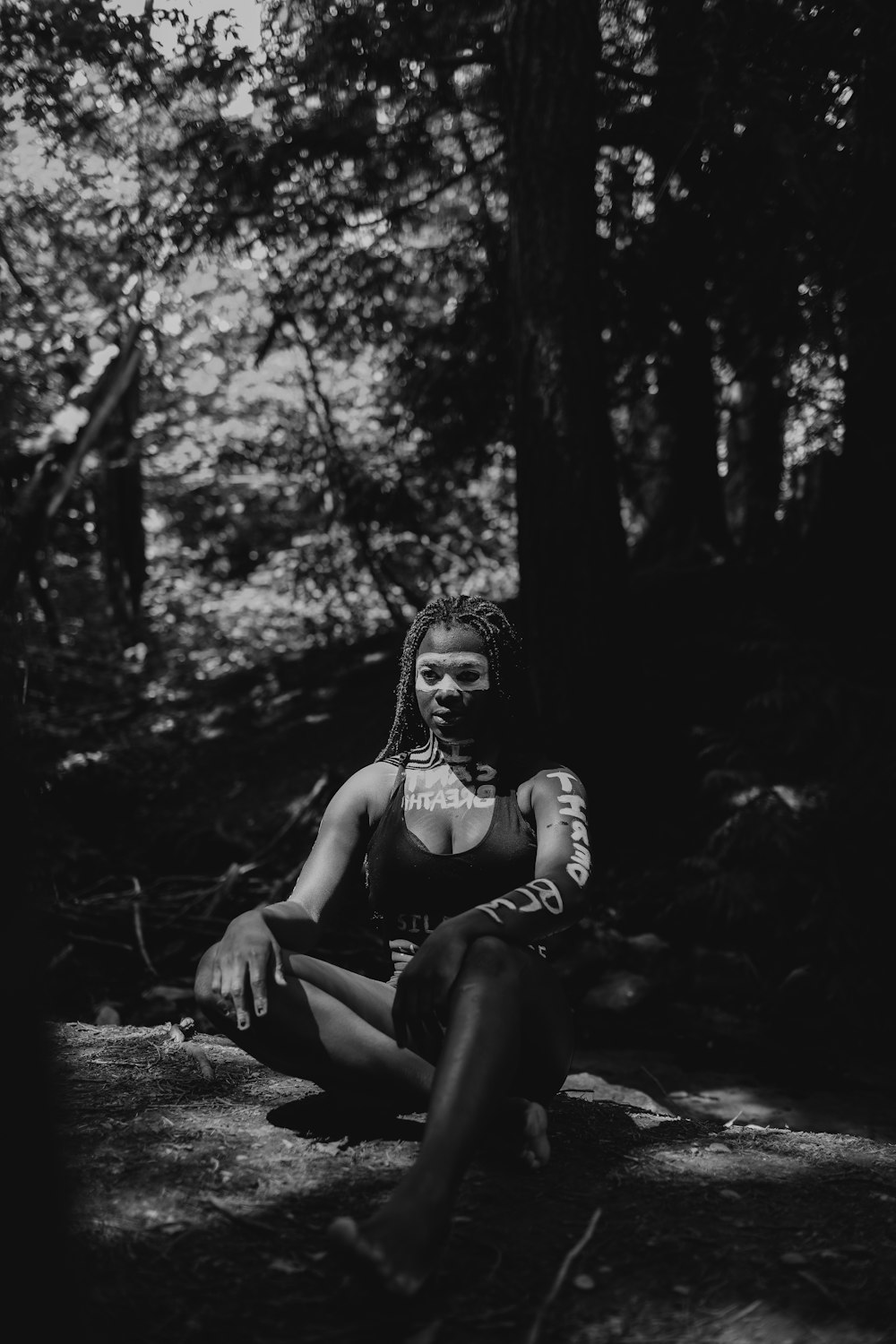 grayscale photo of woman in tank top sitting on ground