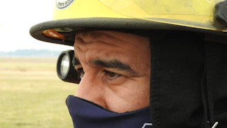 A close-up of a firefighter's hand holding a protective SCBA mask cover against a smoky background.