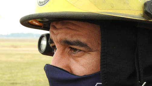 A close-up of a firefighter's hand holding a protective SCBA mask cover against a smoky background.