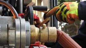 Close-up of a technician inspecting a double diaphragm pneumatic pump in an industrial setting.