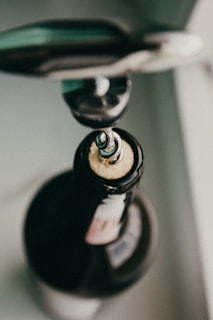 Close-up of a stylish corkscrew opening a wine bottle on a wooden table