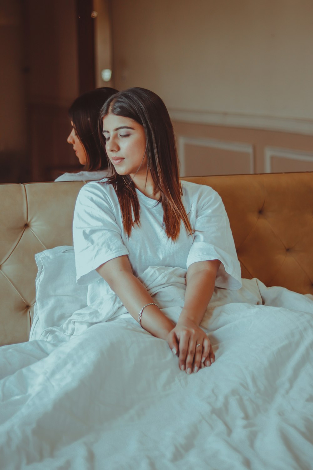 mujer con camisa blanca sentada en la cama