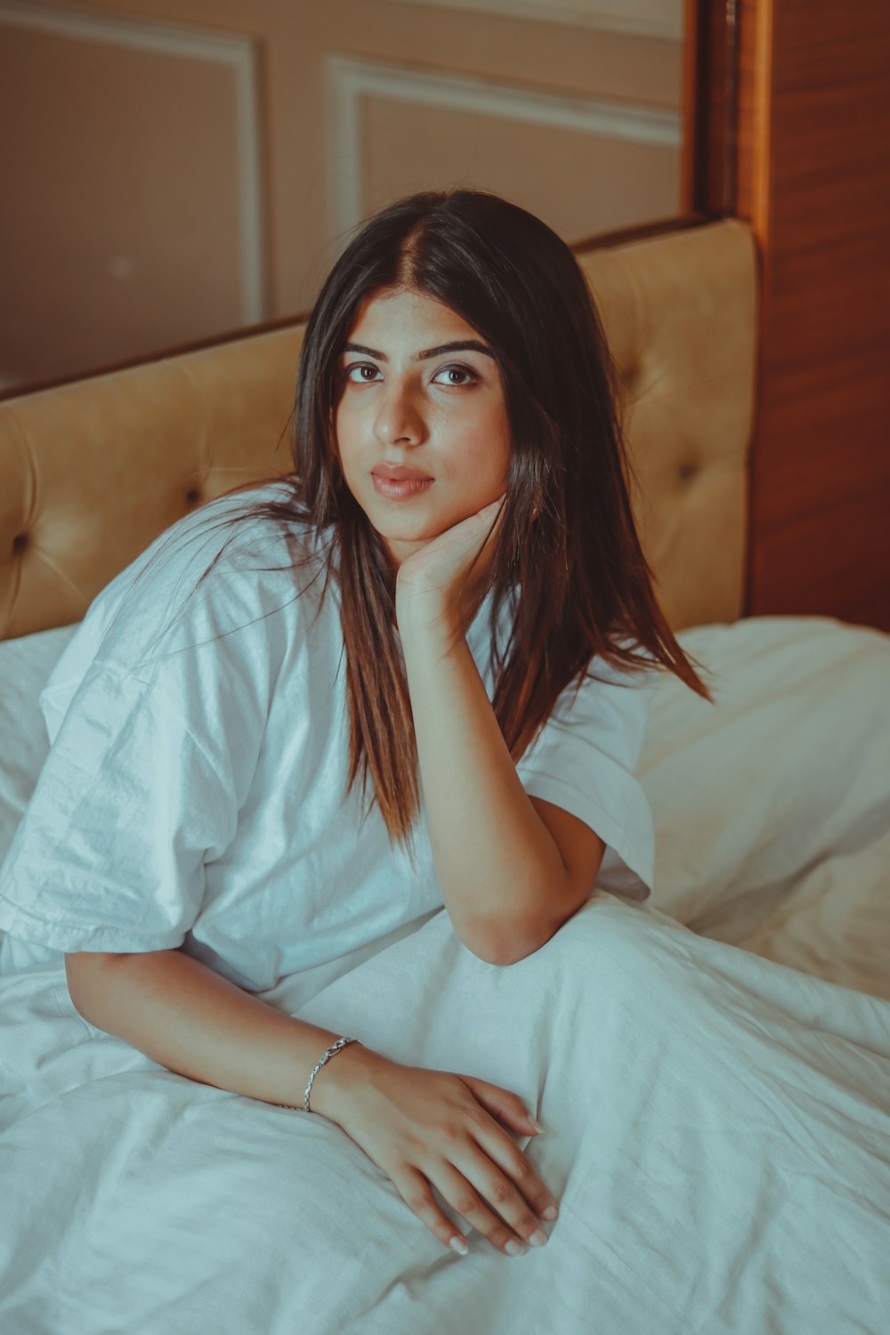woman in white t-shirt sitting on bed