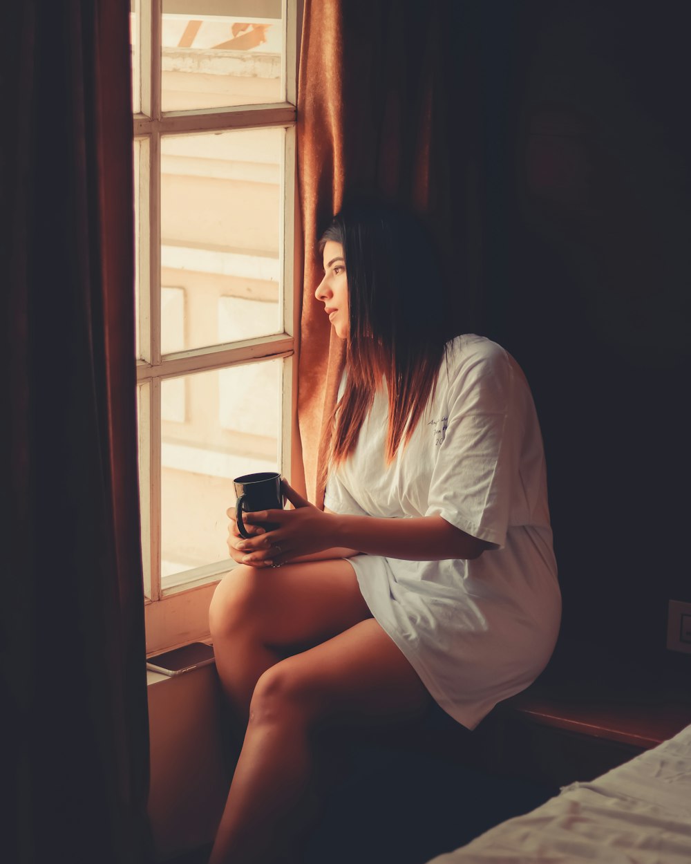 woman in white t-shirt sitting on window