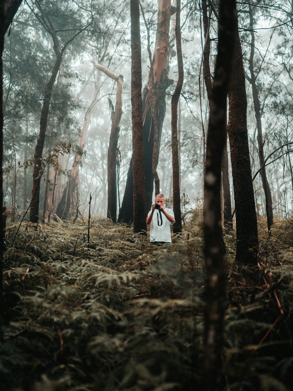 a woman standing in a forest holding a camera