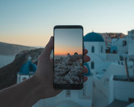 person holding black smartphone taking photo of city during daytime