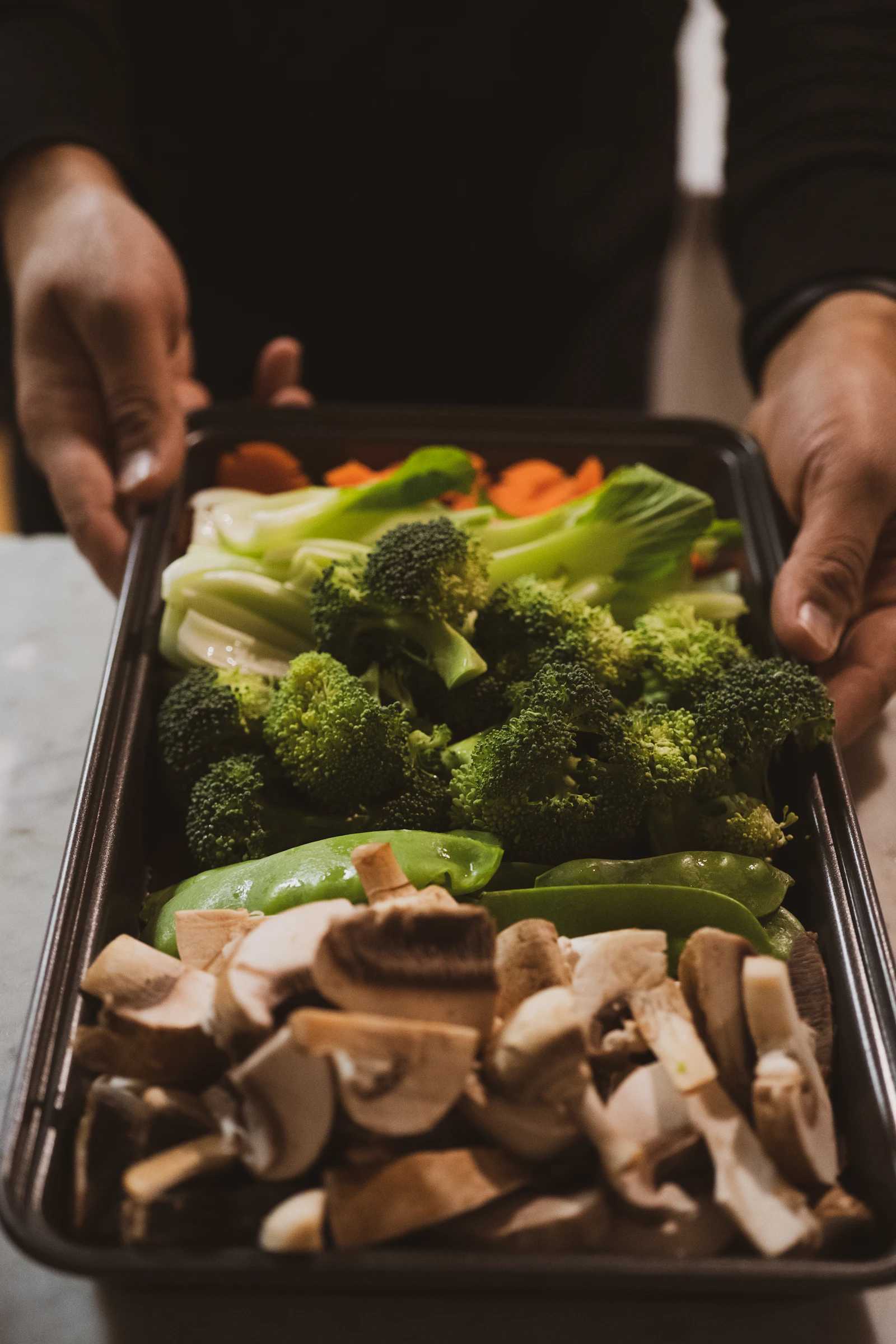 Plat de légumes frais coupés prêts à passer au four : brocolis, champignons et carottes