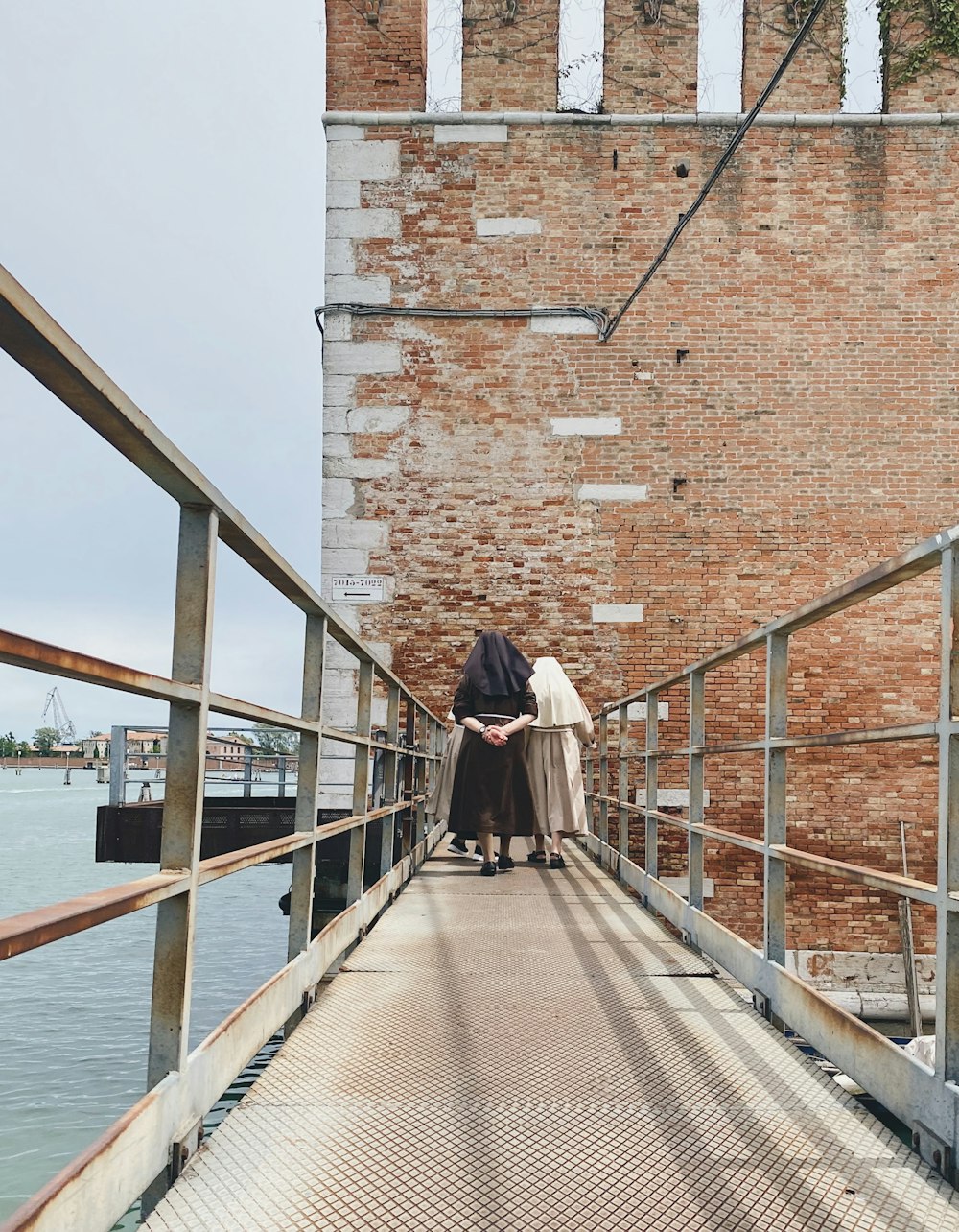 woman in black and white long sleeve dress walking on brown wooden dock during daytime