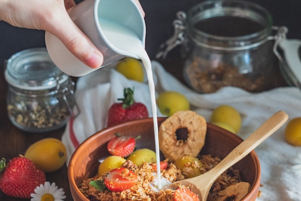 person holding white plastic spoon and brown wooden ladle