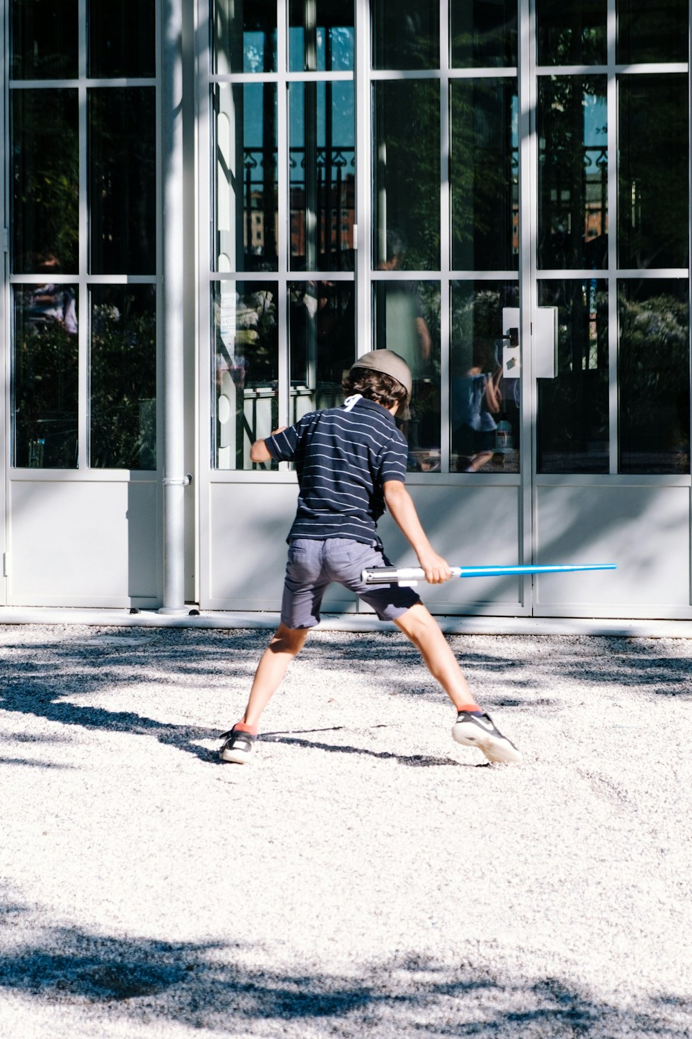 man in black and white stripe shirt and black shorts walking on sidewalk during daytime