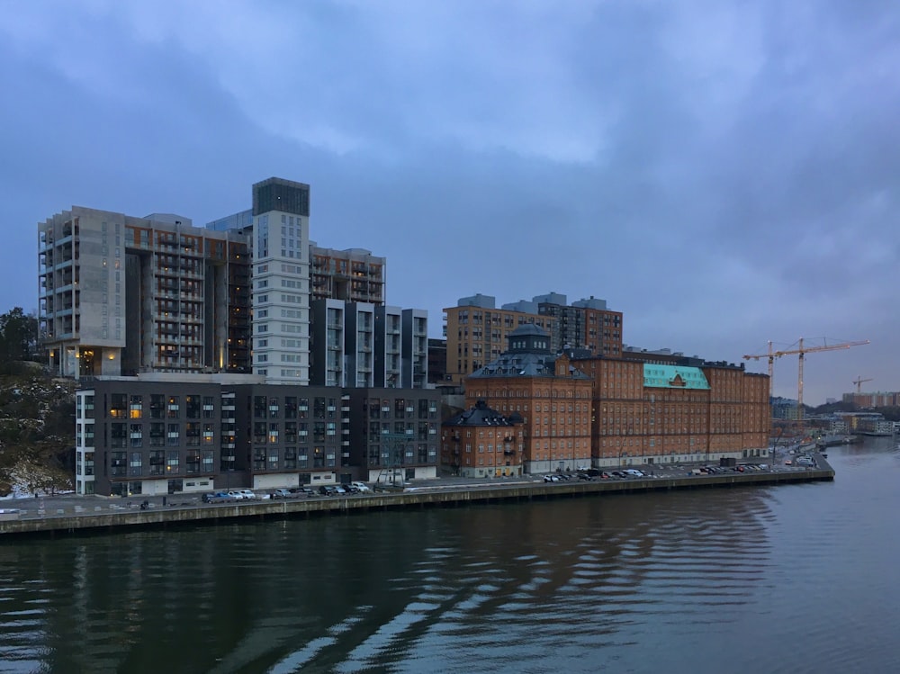 city buildings near body of water under cloudy sky during daytime