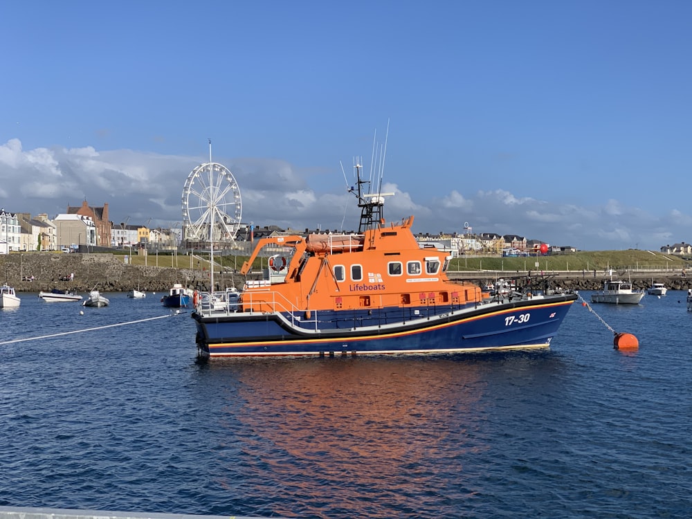 orange and white ship on sea under blue sky during daytime