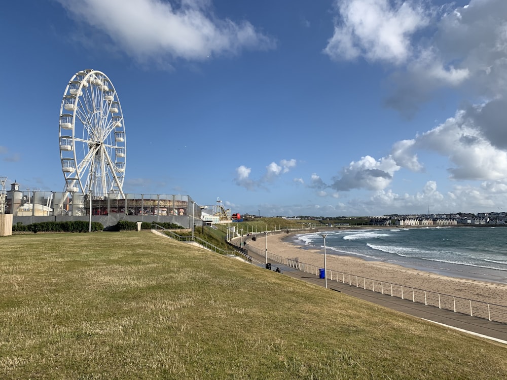 white ferris wheel near body of water under blue sky during daytime