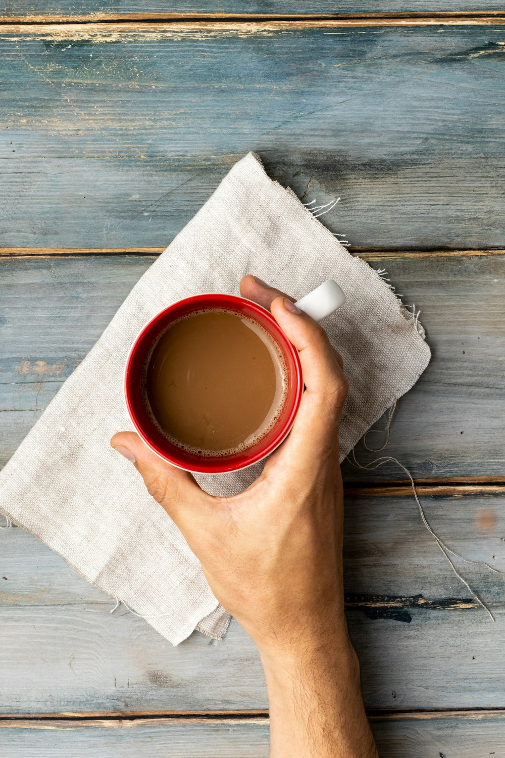 person holding white ceramic mug with red liquid