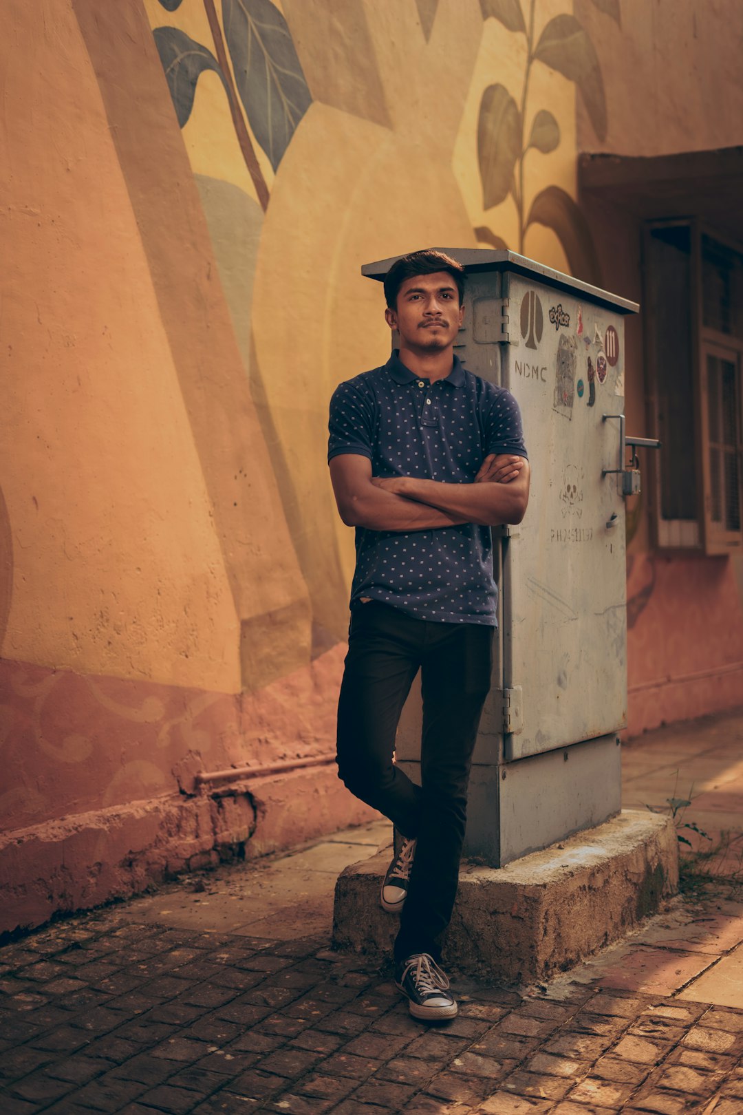 man in black crew neck t-shirt and black pants standing beside brown concrete wall during