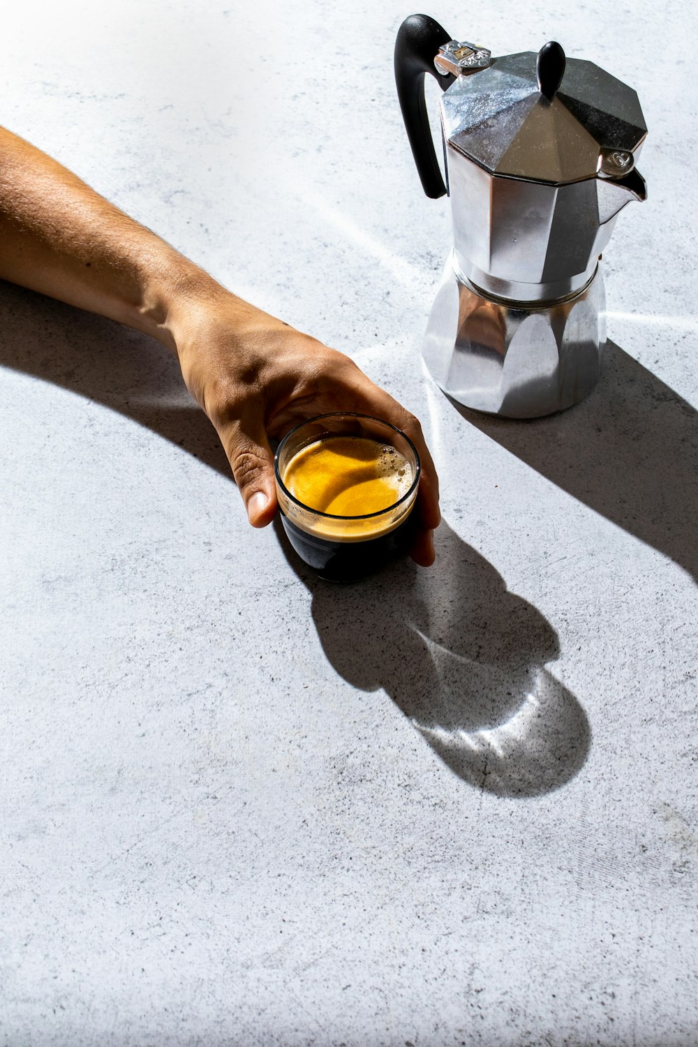 person holding clear glass mug with brown liquid