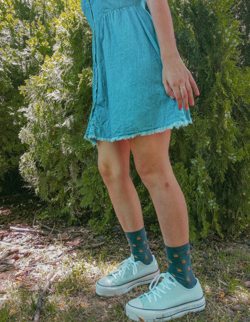 woman in blue dress and white shoes standing on green grass field