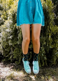 woman in blue skirt and white socks standing on green grass