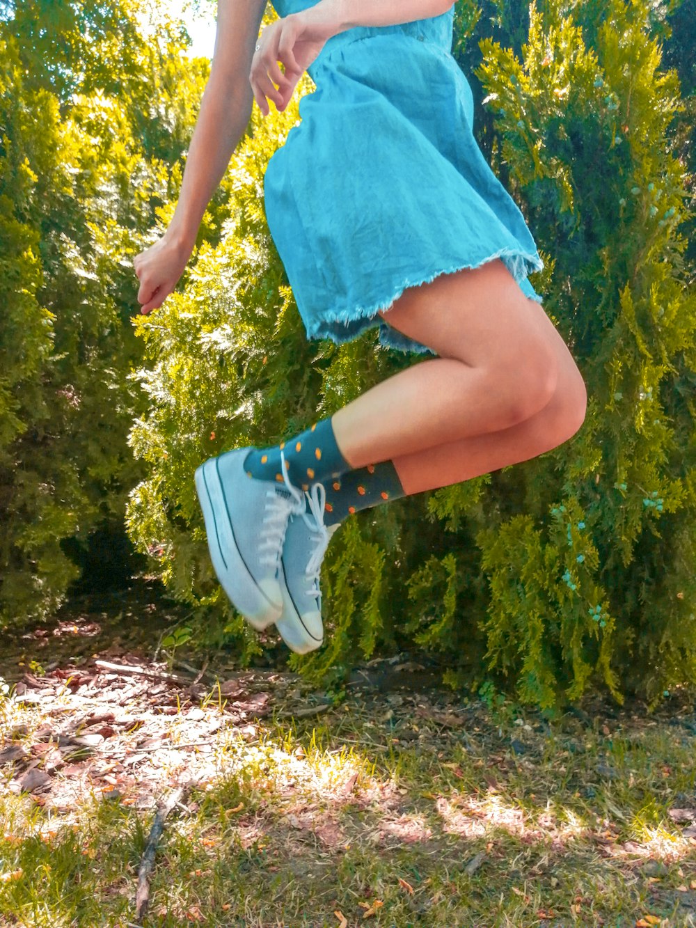 person in blue skirt and white sneakers standing on green grass field during daytime